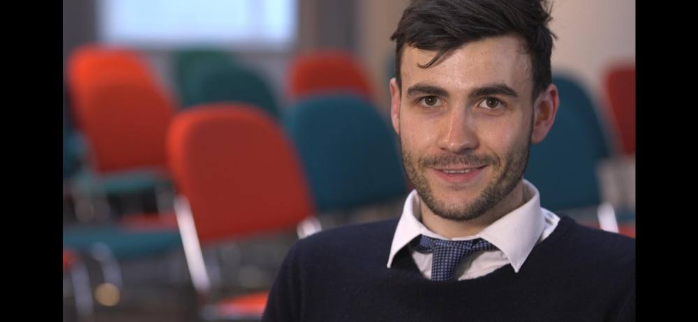 Thomas in shirt and tie, interviewed in a newsroom