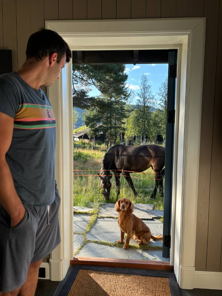 Thomas at the cabin door, a horse and dog outside